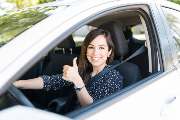Portrait of smiling attractive woman showing thumbs up while driving new car
